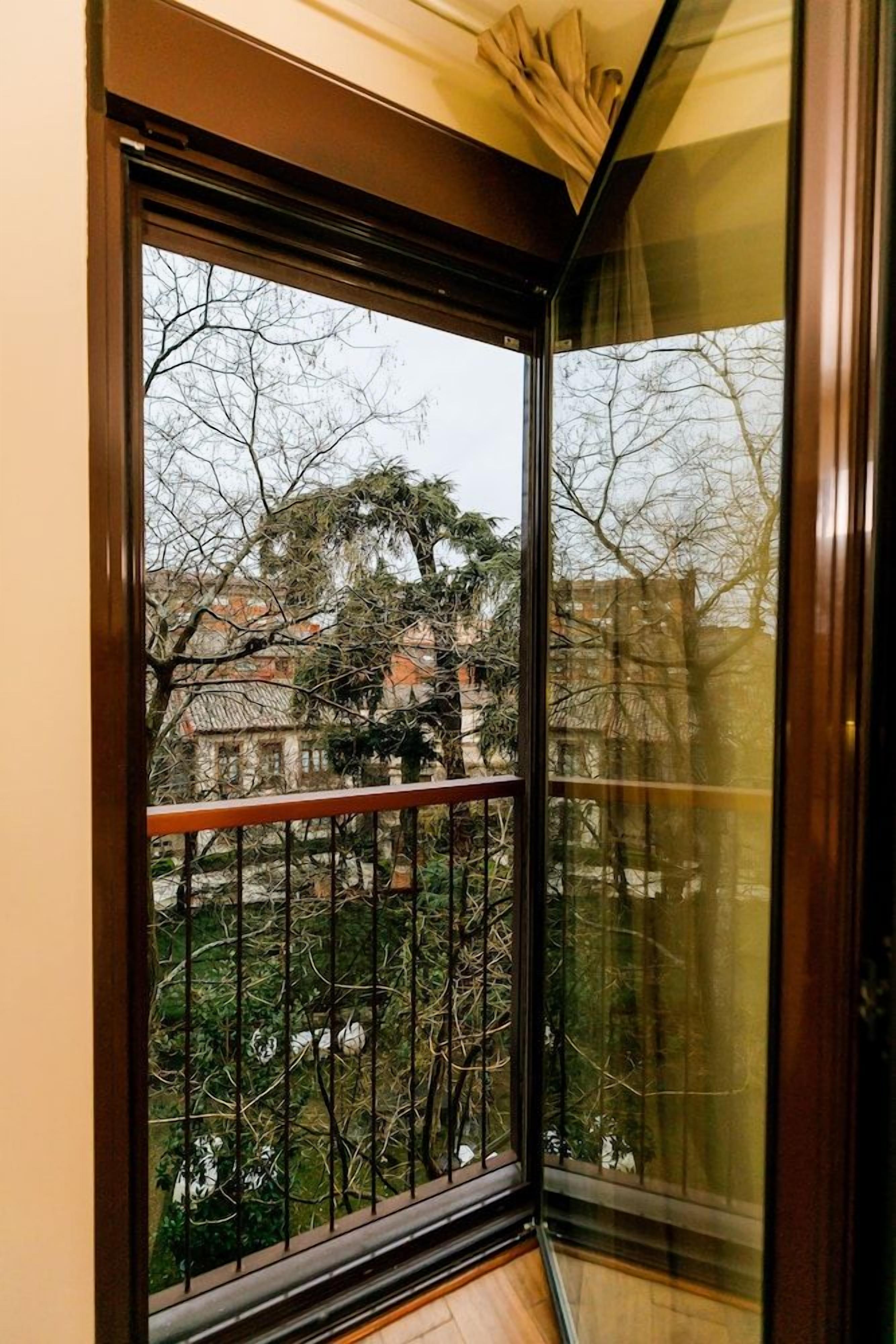 Una habitación con un ventanal grande, suelo de madera y barandilla de metal.
