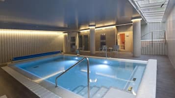 Una piscina interior con techo de cristal, vestuario y zona de duchas.