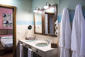 Un baño con lavamanos doble, un espejo con iluminación y toallas colgadas en la pared.