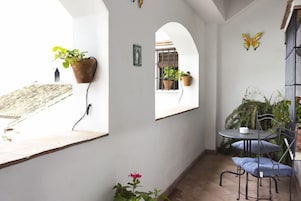 Un pequeño patio con una mesa, sillas, plantas en macetas y un adorno con forma de mariposa.