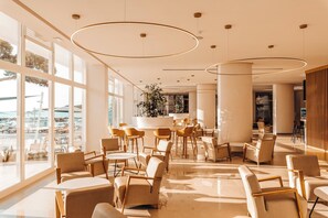 A modern hotel lobby with large windows, a central seating area, and a view of the sea. - Sirenis Hotel Goleta And Spa (Ibiza Town)
