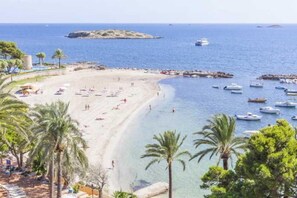 A beach with boats, palm trees, and a clear sky. - Sirenis Hotel Goleta And Spa (Ibiza Town)