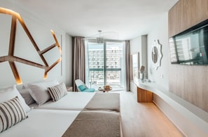Una habitación de hotel moderna con una cama grande, un sofá, una mesita y un televisor.