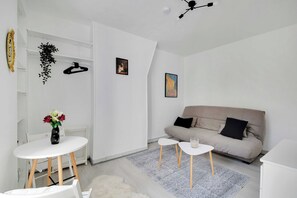 Ein minimalistisches Wohnzimmer mit einer Couch, einem kleinen Tisch und einer hängenden Pflanze.