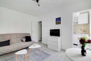 Ein modernes Wohnzimmer mit einer Couch, einem Fernseher, einem kleinen Tisch und einer dekorativen Vase.