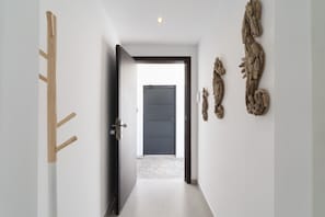 Un pasillo con puerta de madera, una puerta negra al final y esculturas en la pared.