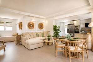 Amplia sala de estar con sofá seccional, mesa de comedor con sillas y cocina equipada con electrodomésticos modernos.