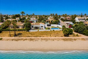 A coastal residential area with houses, a beach, and a clear blue sky.