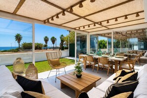 An outdoor patio with a dining area, seating, and a view of the sea.