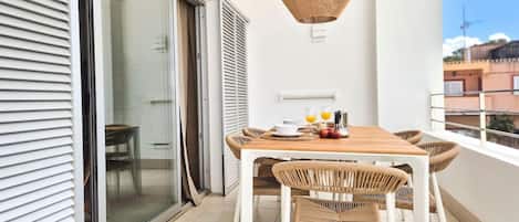 A balcony with a table and chairs, a hanging light fixture, and a sliding glass door leading to a patio.