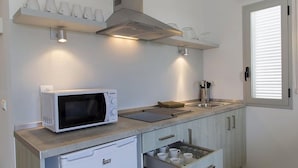 A compact kitchen with a microwave, a toaster, and a sink. - Apartaments Proa Es Pujols (Formentera)