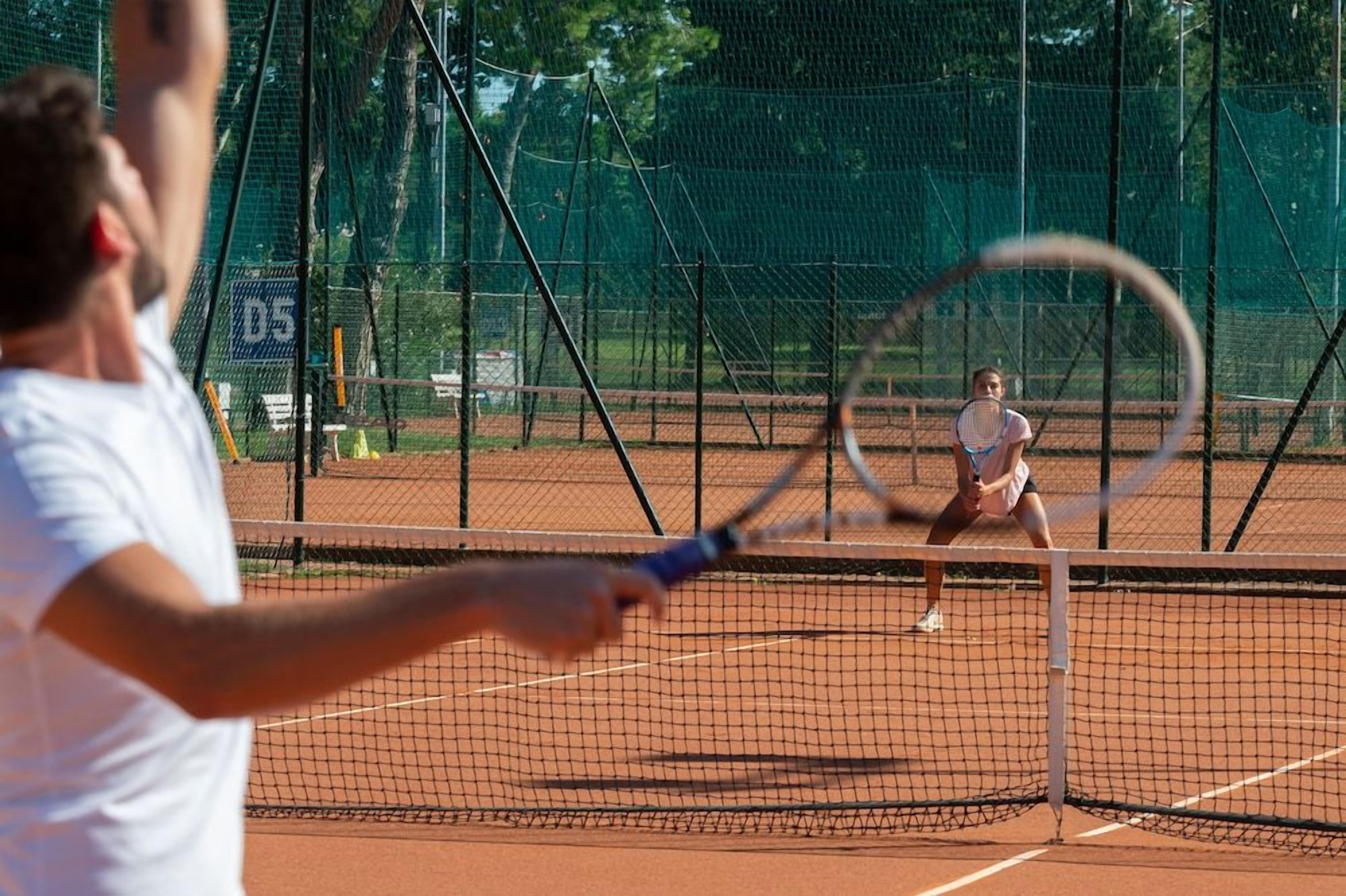 En tennisbane med et net i midten, omkranset af et hegn.