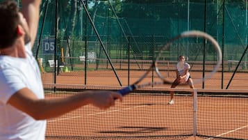En tennisbane med et net i midten, omkranset af et hegn.