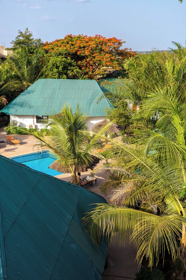 A pool area with a house, palm trees, and a view of the surrounding landscape.