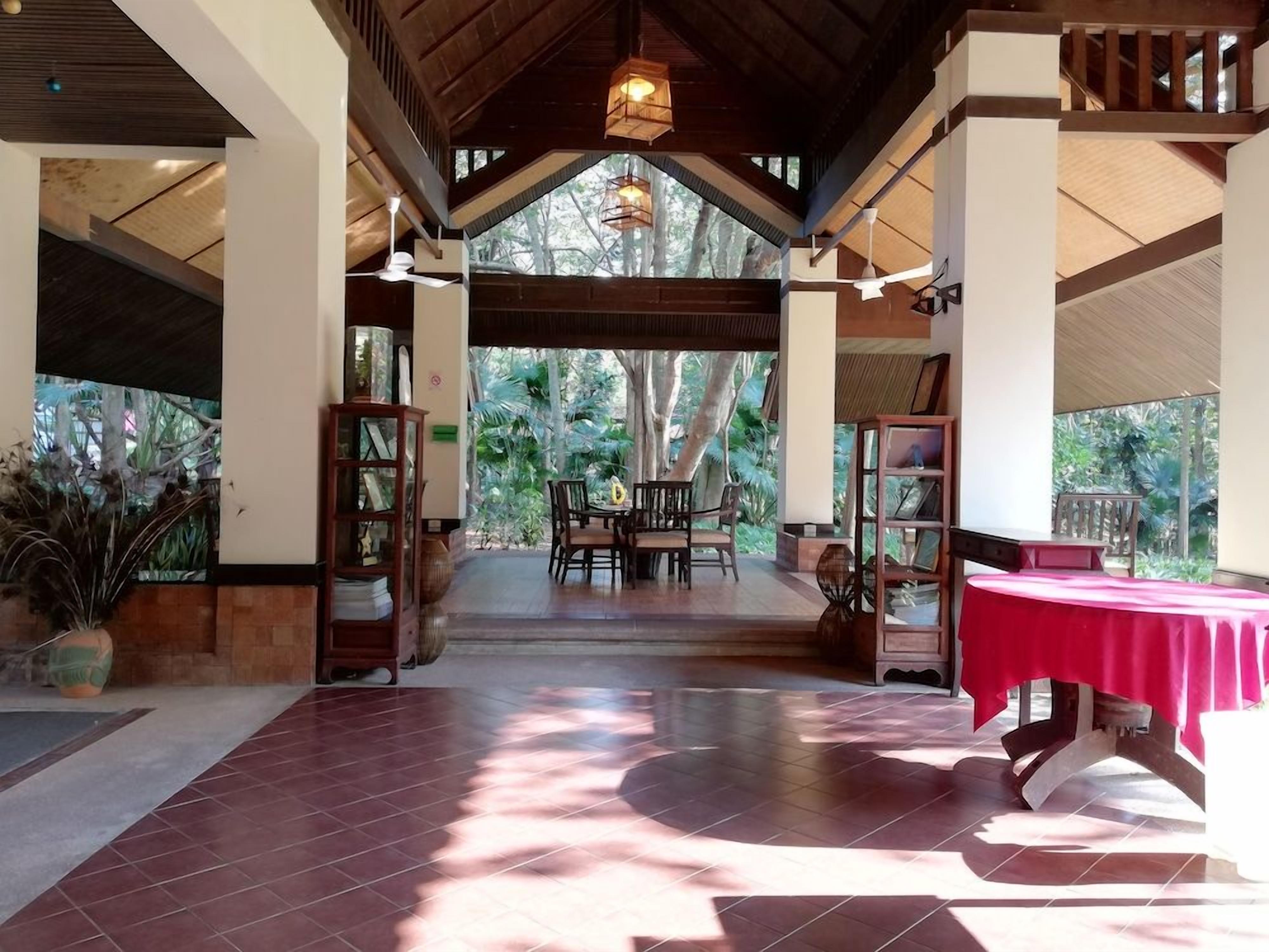 Espaço interno com teto de madeira, mesa de jantar com cadeiras e toalha de mesa vermelha.