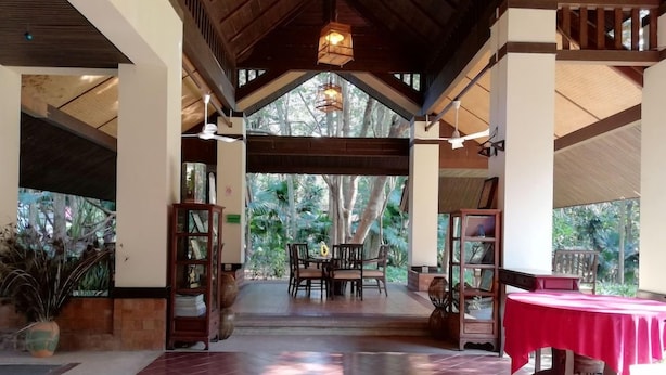 An indoor area with a wooden ceiling, a dining table with chairs, and a red tablecloth. - Wanathara Health Resort & Spa (Wang Thong)