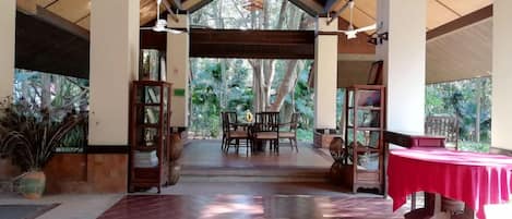 Espaço interno com teto de madeira, mesa de jantar com cadeiras e toalha de mesa vermelha.