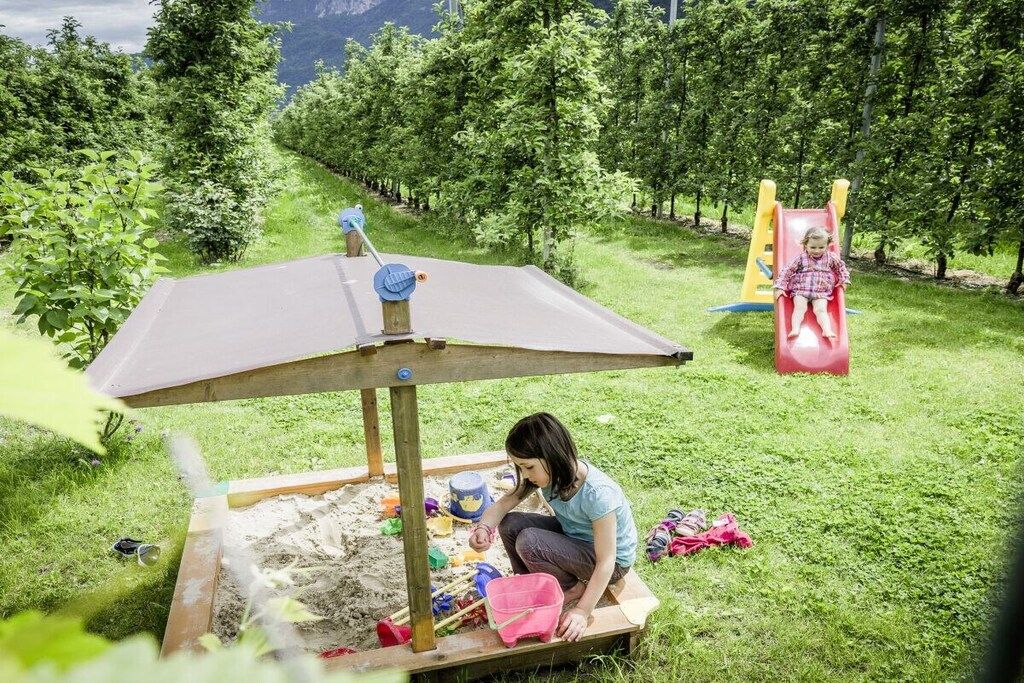 A child playing on a slide in a grassy area with trees in the background.