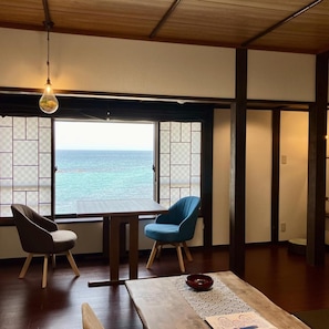 A room with a view of the sea, a table with a red bowl, and two chairs. - Uminone (Toyooka)