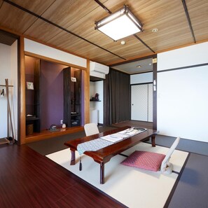 A traditional Japanese-style room with tatami flooring, a low wooden table, and a sliding door leading to another room. - Uminone (Toyooka)