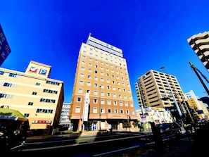 A multi-story hotel with a prominent sign, a parking sign, and a clear blue sky. - Toyoko Inn Shonan Chigasaki-eki Kita-guchi (Chigasaki)