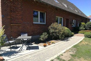 A brick house with a patio, a table, and chairs. - Holiday apartment in Ladbergen with barbecue (Ladbergen)