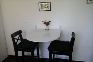 A small dining area with a white table and two black chairs. - Holiday apartment in Ladbergen with barbecue (Ladbergen)
