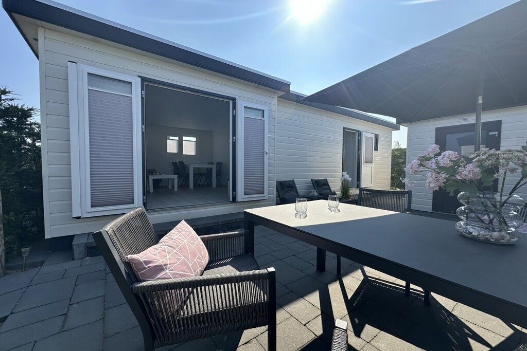 An outdoor patio area with a table and chairs, a sliding glass door leading to an interior space, and a covered area with a table and chairs.