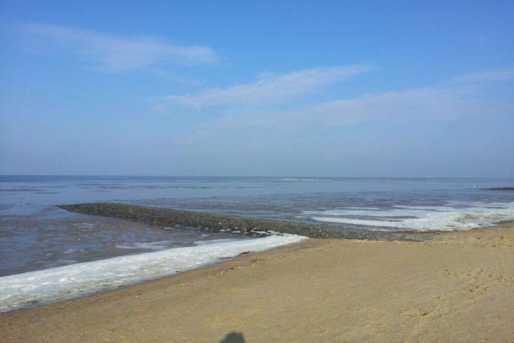 A beach with a rocky shoreline and calm waves.