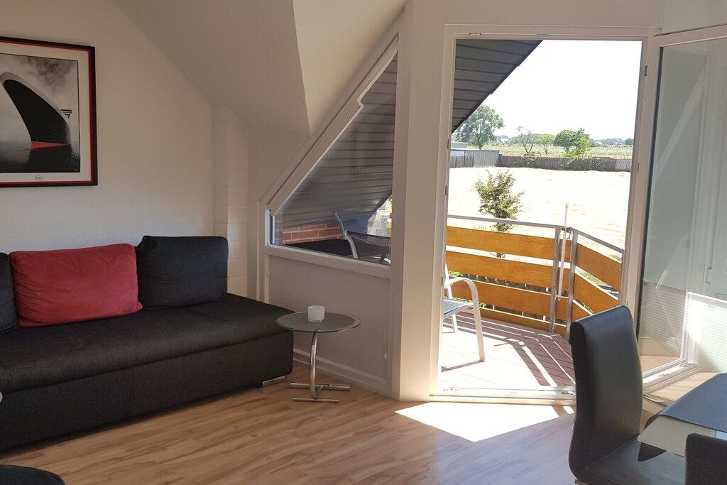 En moderne stue med en sofa, et lille bord og en balkon med udsigt.