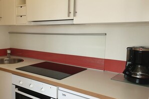 A kitchen with a stove, a coffee maker, and a sink. - Vinnenhus Apartment 8 (Cuxhaven)