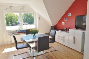 A dining area with a table, chairs, and a vase of flowers. - Vinnenhus Apartment 8 (Cuxhaven)