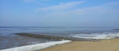 A beach with a rocky shoreline and calm waves.