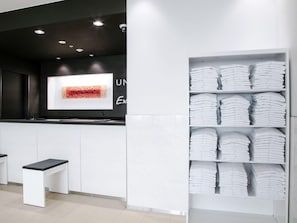 A reception area with a counter, a television screen, and a shelf with folded towels. - Unizo Inn Express Morioka (Morioka)