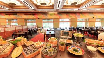 A buffet setup in a hotel dining area with multiple tables and chairs, and a large window providing natural light.