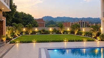 A swimming pool with a surrounding garden and a view of distant buildings.