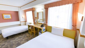 Een hotelkamer met twee enkele bedden, een bureau met stoel, een spiegel en een raam met gordijnen.