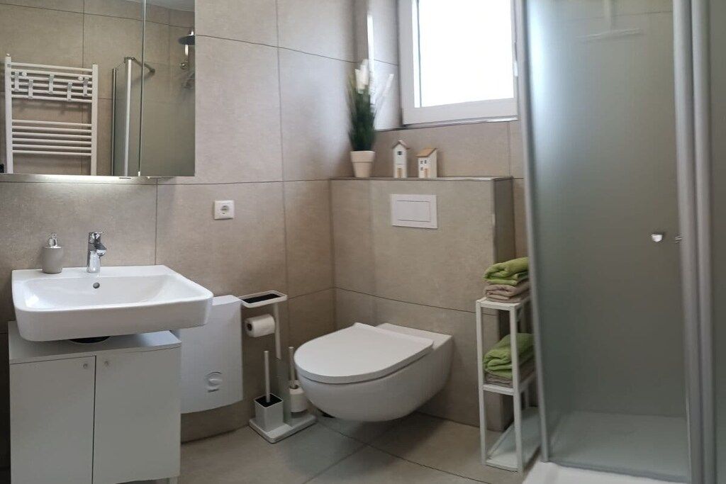 Casa de banho moderna com lavatório, sanita e chuveiro.