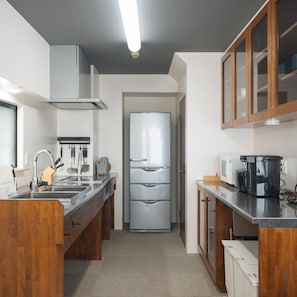 A modern kitchen with stainless steel appliances, wooden cabinets, and a built-in microwave. - Tabiyu Abrigo Hotel (Kobe)