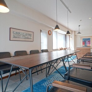 A conference room with a long table, chairs, pendant lights, a framed picture on the wall, and a clock. - Tabiyu Abrigo Hotel (Kobe)