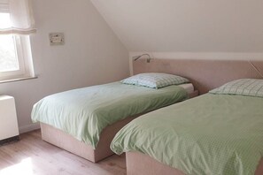 A room with two single beds, a window with curtains, a bedside lamp, and a thermostat on the wall. - Holiday apartment with 1 bedroom (Warendorf - Hoetmar)