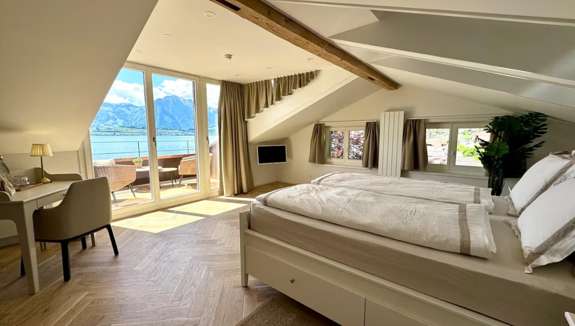 Un dormitorio con una cama grande, un escritorio y vistas a las montañas.