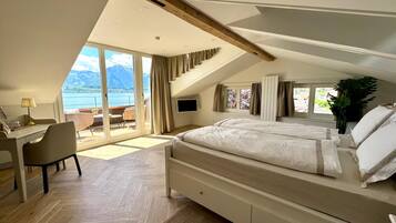 Un dormitorio con una cama grande, un escritorio y vistas a las montañas.
