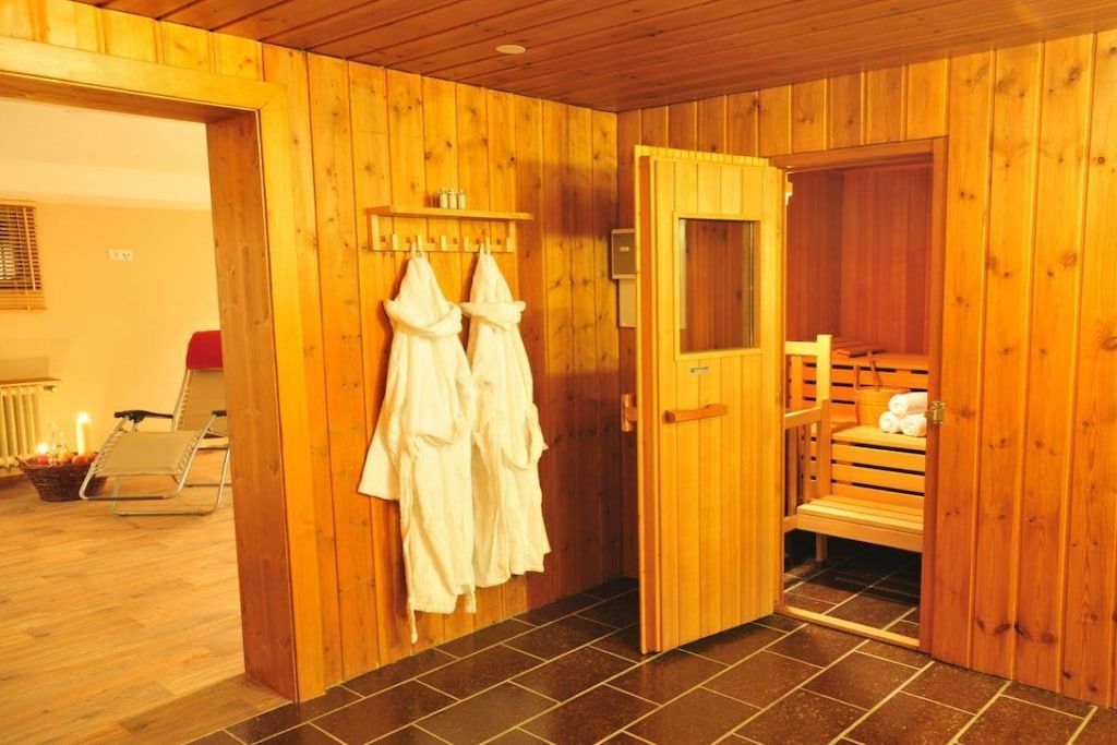 Een houten sauna met een bank, handdoeken en een klein plankje.