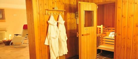 Een houten sauna met een bank, handdoeken en een klein plankje.