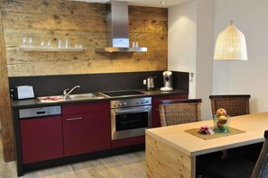 Eine moderne Küche mit einer Holz-Akzentwand, Edelstahlgeräten und einem Essbereich mit Holztisch.