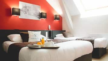 A hotel room with two beds, a red accent wall, and a skylight.
