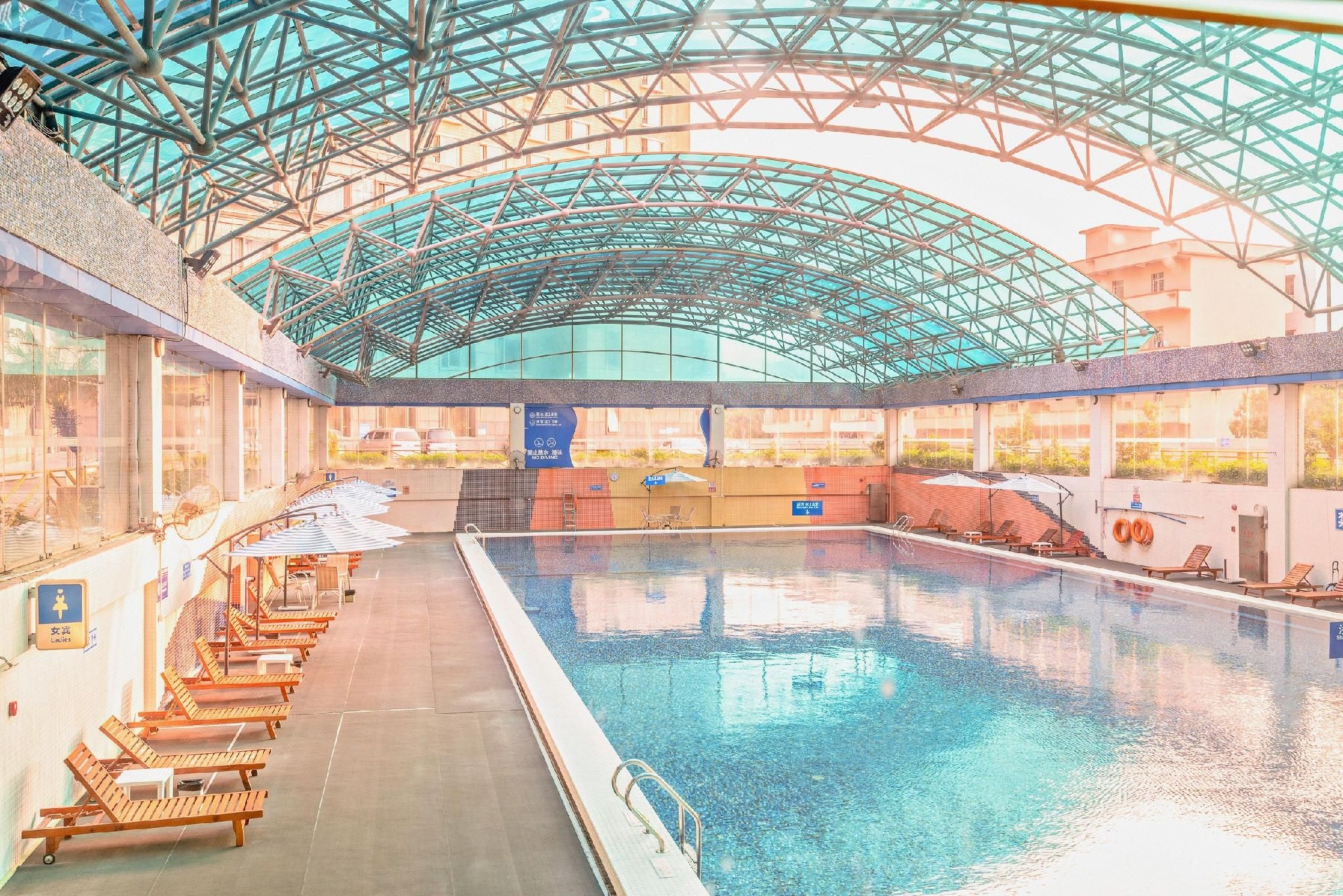 Piscina interna com teto de vidro, várias pistas de natação e cadeiras de descanso nas laterais.