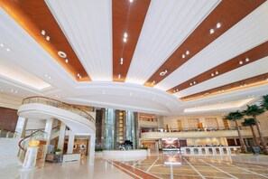 A spacious lobby with a curved ceiling, multiple levels, and a central atrium. - H J Grand Hotel Guangzhou (Guangzhou)