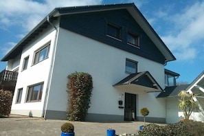 Een herenhuis met een donker dak, witte muren en een klein voortuintje.